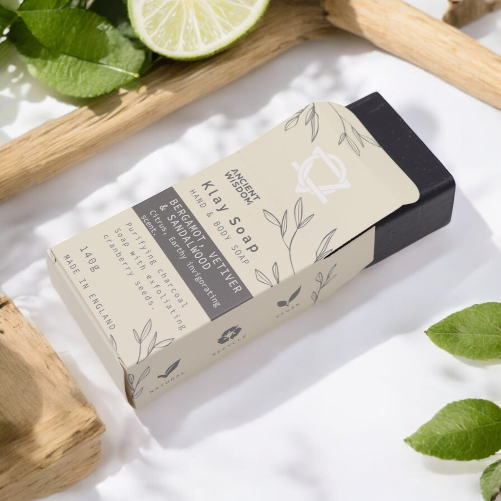 Klay Soap - Bergamot & Sandalwood. A rectangular bar of natural, dark-coloured soap with visible cranberry seeds for exfoliation. The soap is infused with Fuller's earth clay and activated charcoal for detoxifying properties.